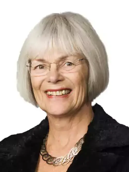 Portrett av en eldre kvinne med hvitt hår, halskjede og sort genser.
