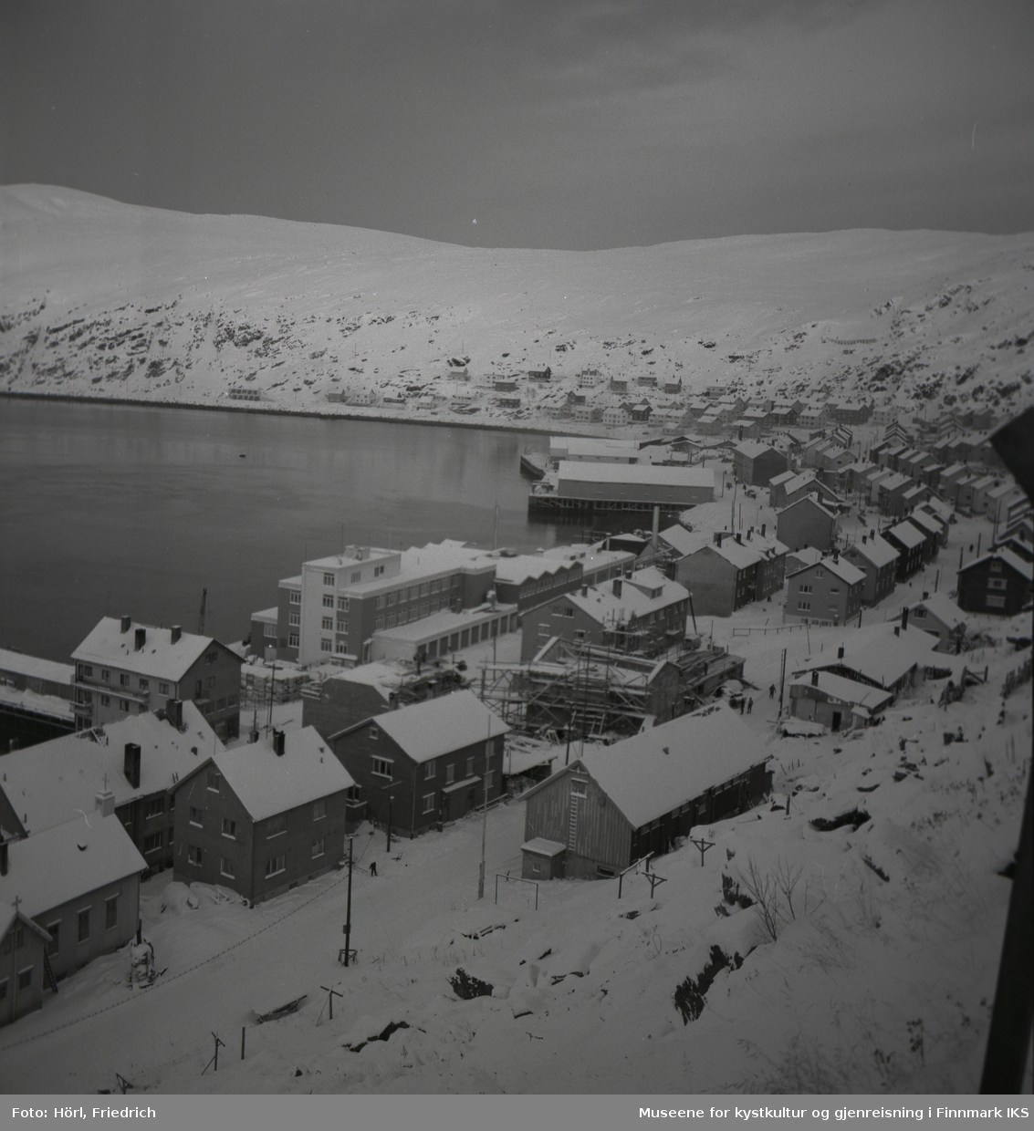 Oversikt over deler av Hammerfest sentrum og Molla i vinteren 1957/1958. Bildet er fotografert fra Salenfjellet. Sentralt i bildet ser man den katolske kirke St. Mikael som bygges. Ved havna ser man også byggene til Findus og Hauans materialhandel.