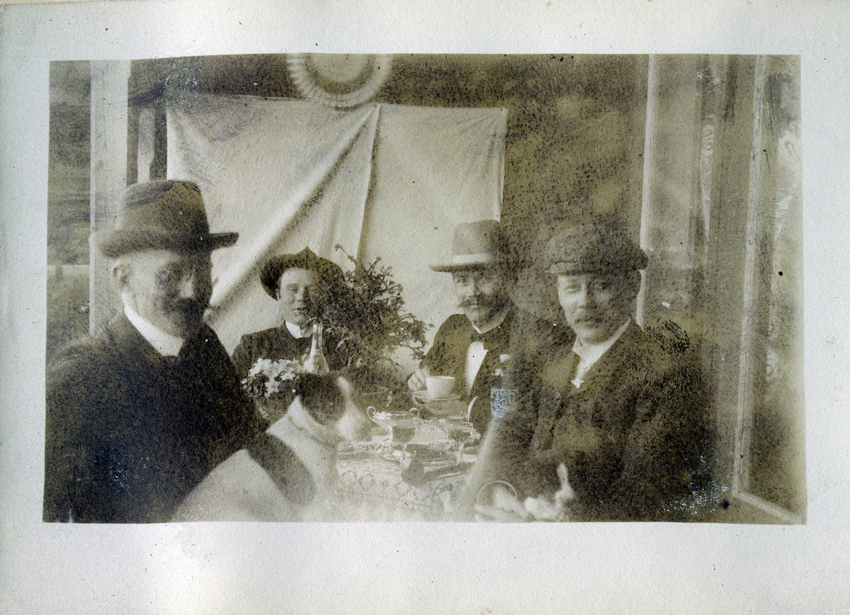 Fire menn sitter ved et bord 1904.
Hellenerne.
Bilde er fra fotoalbum GM.036887.