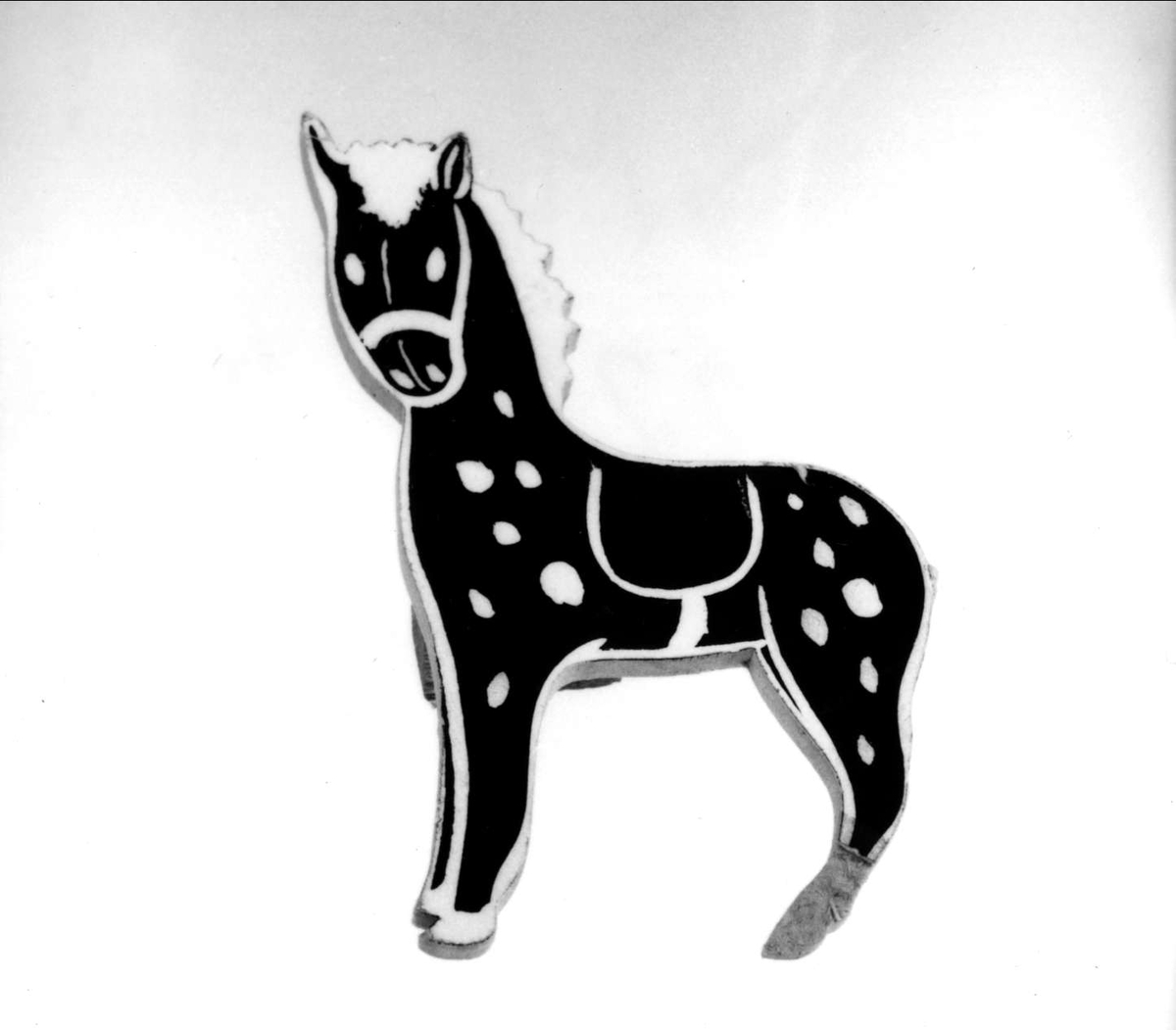 Reklamhäst av treplexplatta, bemålad svart och vit på en sida. Från Hästens skofabrik.