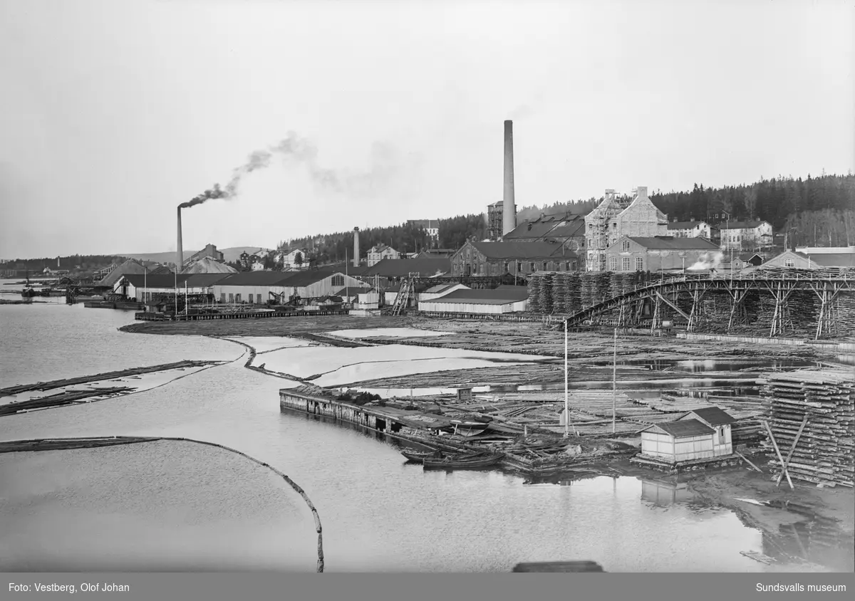 Vy över Ljungan mot Essviks sulfitfabrik med pågående tillbyggnation. Längre bort syns Nyhamns sulfitfabrik och i vänsterkant skymtar Klampenborgs sågverk.