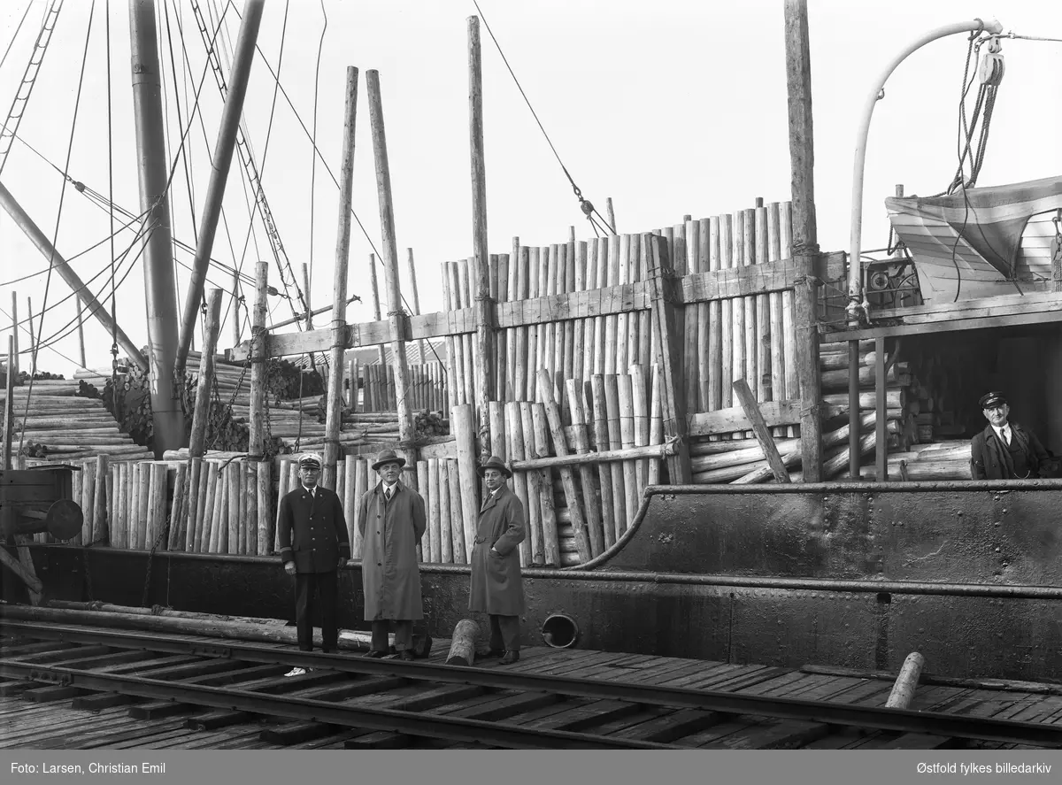 Lastebåt med tømmer, antakelig Sarpsborg havn. Personer er ukjente, noen fra havnevesenet?