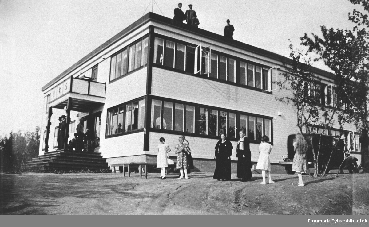 Norske Kvinners Sanitetsforenings feriested "Soltun" i Skiippagurra fotografert sommeren rundt 1930. Noen kvinner og jenter foran huset. Tre menn står på taket og noen menn står på trappa. Foran huset er parkert en bil.