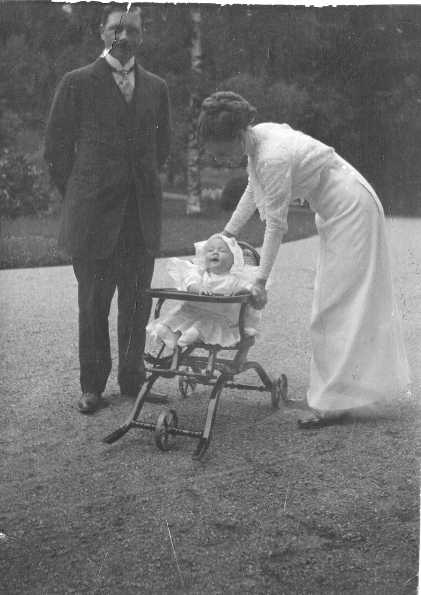 Foto av mann og kvinne sammen med baby i barnestol. Til venstre er trolig godseier Cato Aall