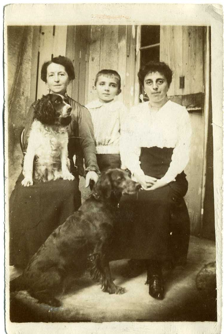 Två kvinnor, en pojke och två hundar. Kvinnan till vänster är Marie Rongis (alt. Rungis). Kvinnan till höger är möjligen Jeanne Machuron.