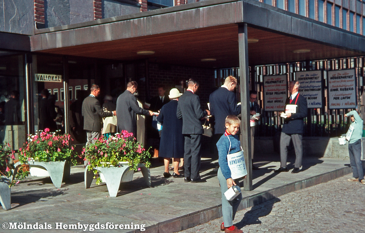 Valsedelsutdelare vid entrén till stadshuset i Mölndal på valdagen, år 1966. Sim 1:35.