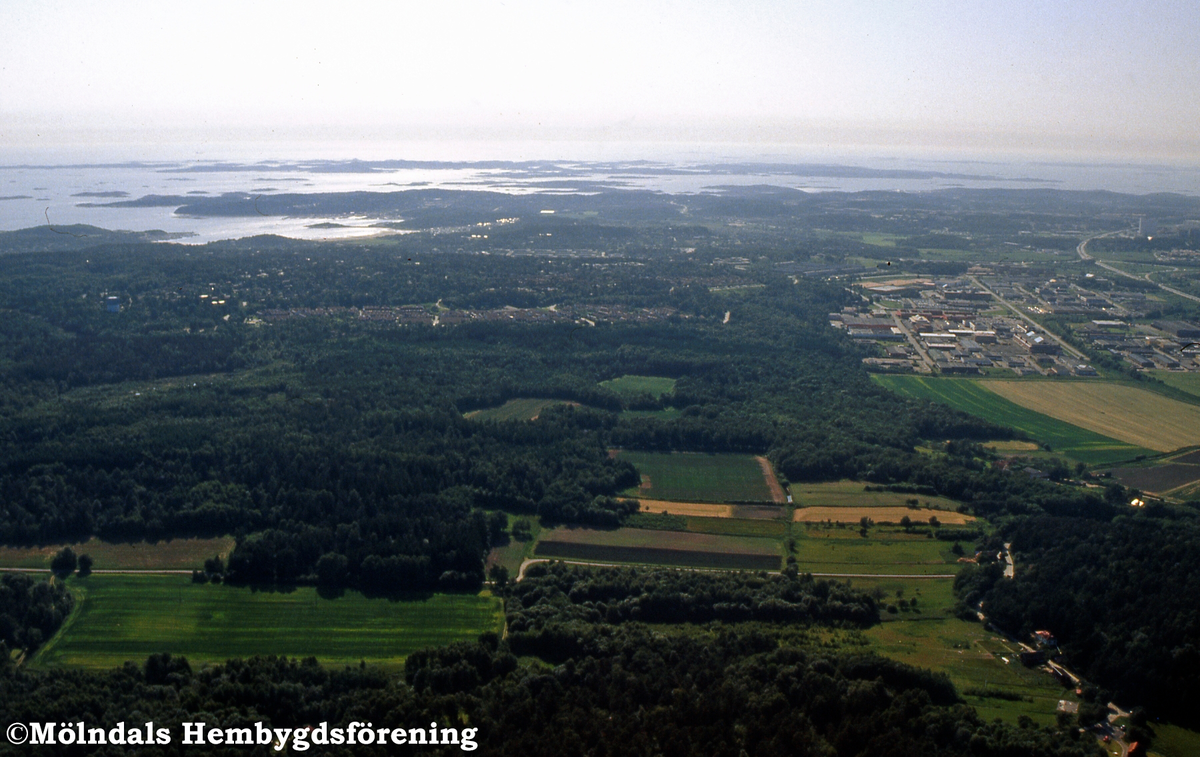 Flygfotografi över markerna i Balltorps berg, Mölndal, den 4/7 1991. Bortom det ses Sisjöns bostäder och industrier. FD 5:13.
