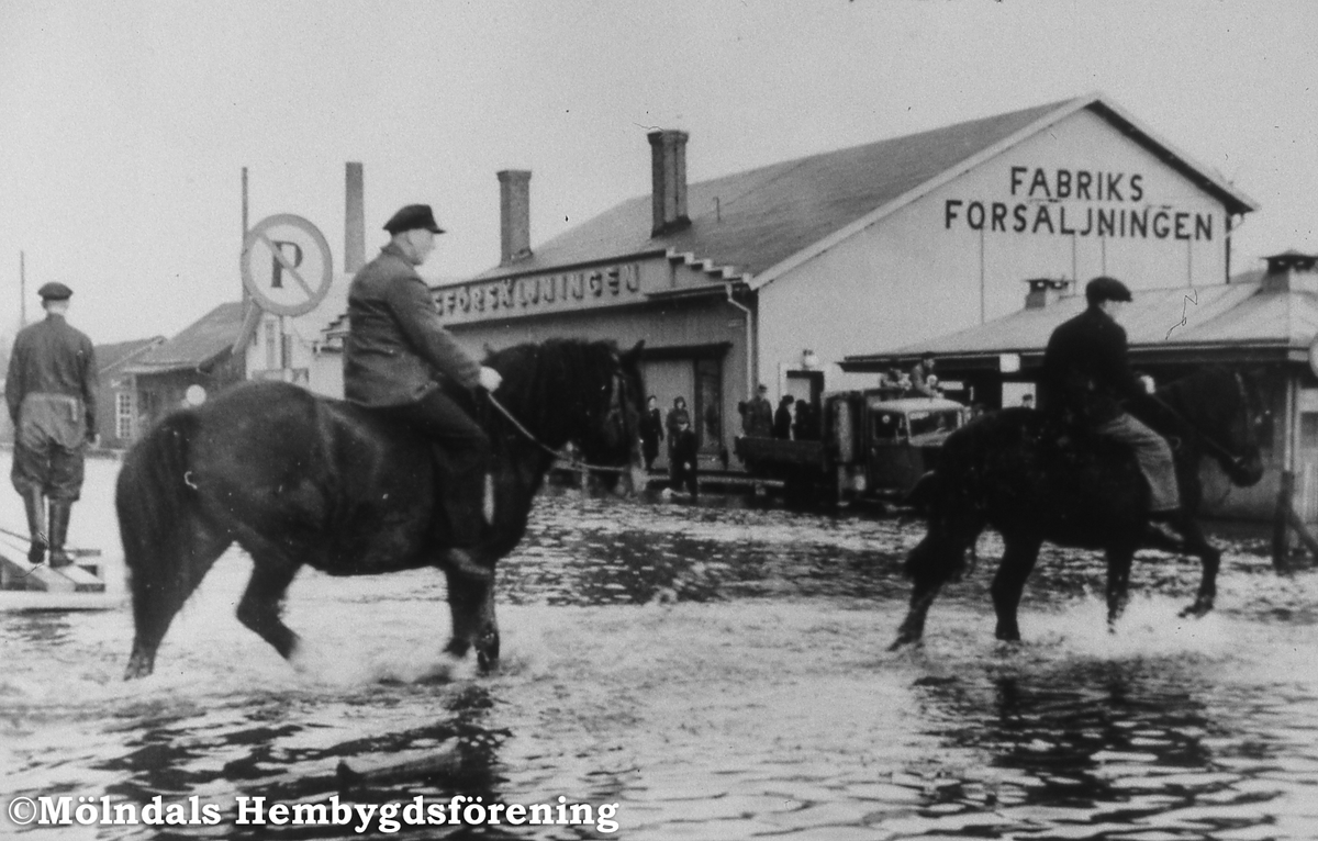 Översvämning med ryttare i Mölndalsbro, okänt årtal. Fabriksförsäljningen och pressbyråkiosken.