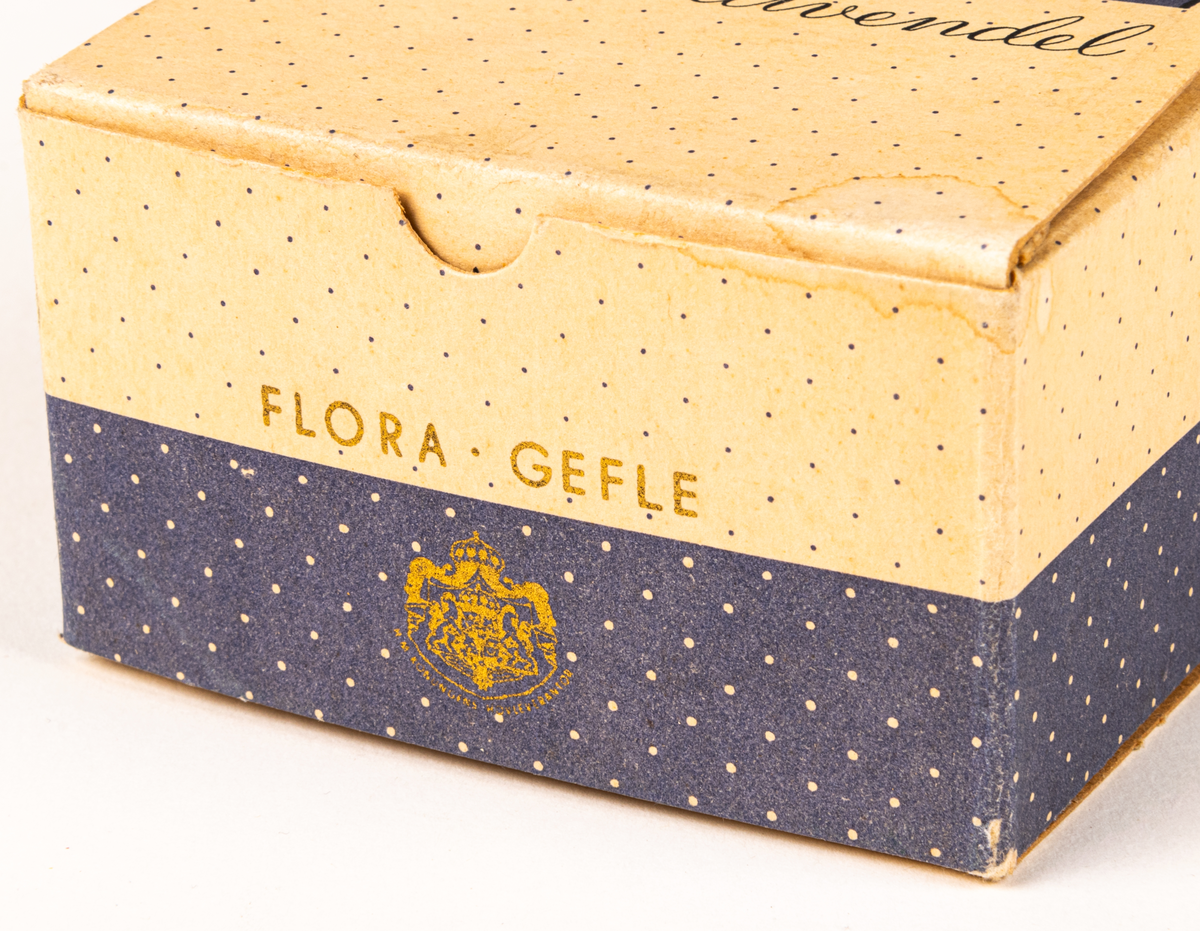 Tvålförpackning av papp. Rektangulär ask med tryck i grått på beige botten. Småprickig, grå fält på sidorna samt text: "Florodol Lavendel" och "FLORA GEFLE".