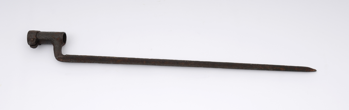 Døllebajonett, muligens av typen M/1849 produsert ved Kongsberg våpenfabrikk i perioden 1850 - 1855, med hulslipt trekantet klinge. Bajonetten festes til geværet ved at døllen tres inn på våpenets løp og så festes med en låsering.