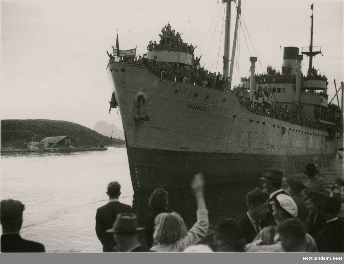 Et stort skip med mange mennesker på dekk.  "Mungo". Trolig bilde av de sovjetiske krigsfangers avskjed. Bilde tatt i Bodø under feiring av freden etter okkupasjonen 1945.