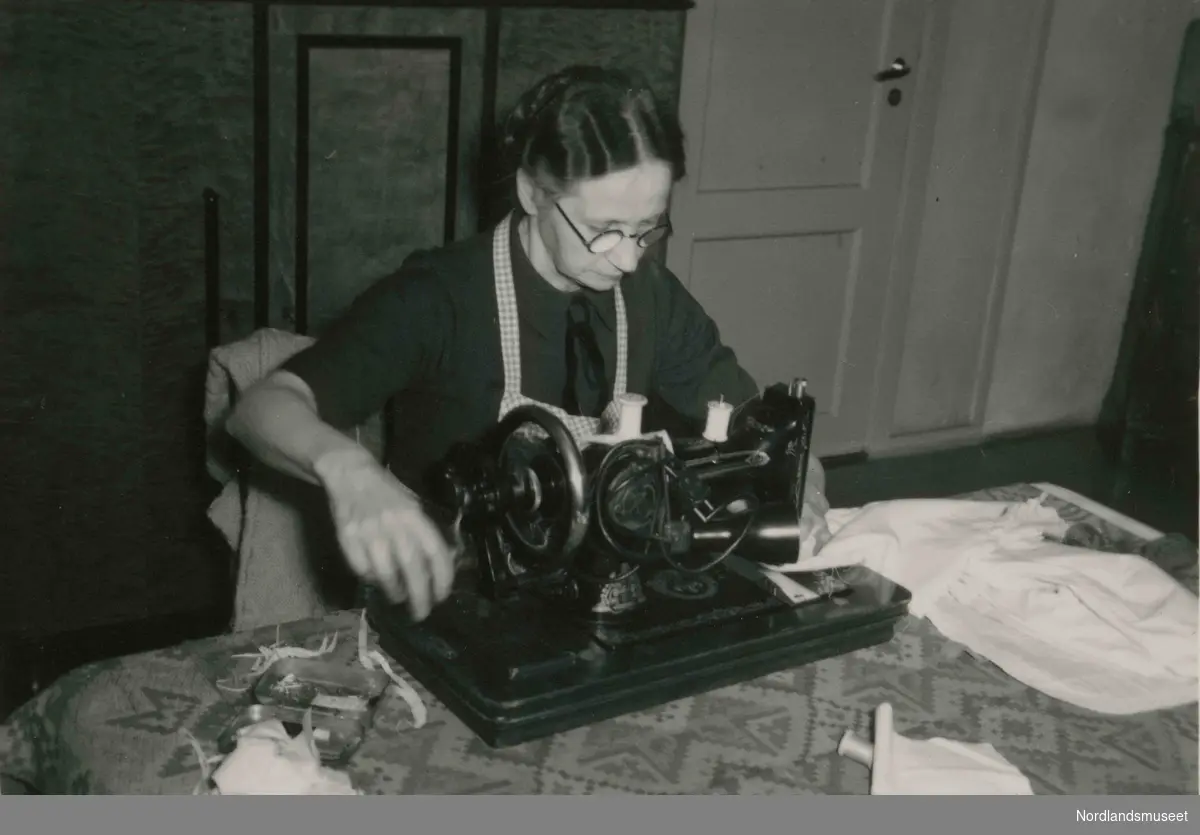 Sydame Signe Larsen håndterer en manuell symaskin. Signe var sydame på systua i brakkebygget.