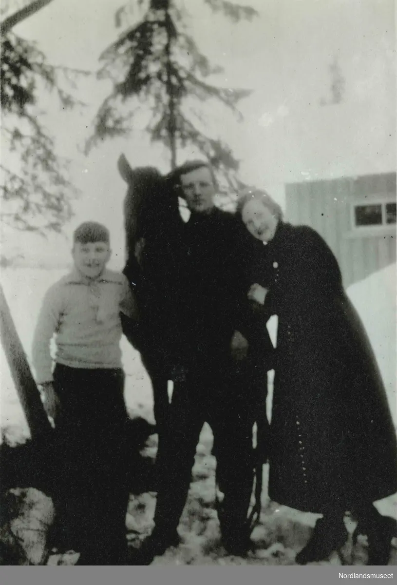 Uklart bilde av en mann, en kvinne og et barn sammen med en hest.