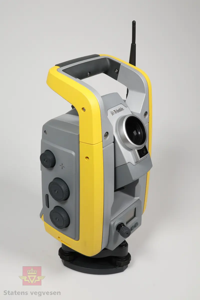 En gul beholder med remmer som inneholder en robot totalstasjon med tilhørende fotplate, adapter, sikteskiver, verktøy, regntrekk, nøkler til beholder, 2stk solblendere, 2stk stylus og en servicerapport.
