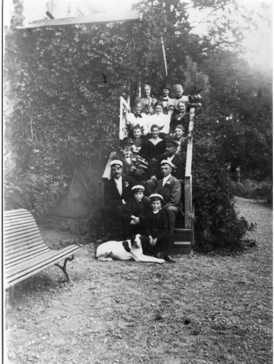 Gruppbild på trappan till övervåningen på Augustendal med far och son Silfverhjelm samt familjen Salomonsson med sönerna Carl och Otto längst ned. Två bilder.