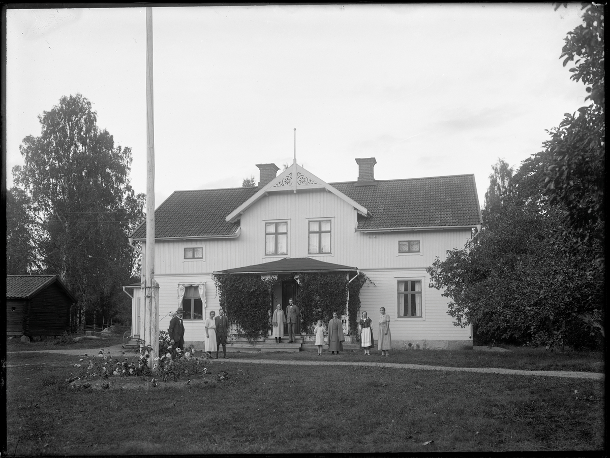 Grupporträtt framför hus. G. Olsson, Bärsta, Kolbäck 
Ur Gustaf Åhmans samling.