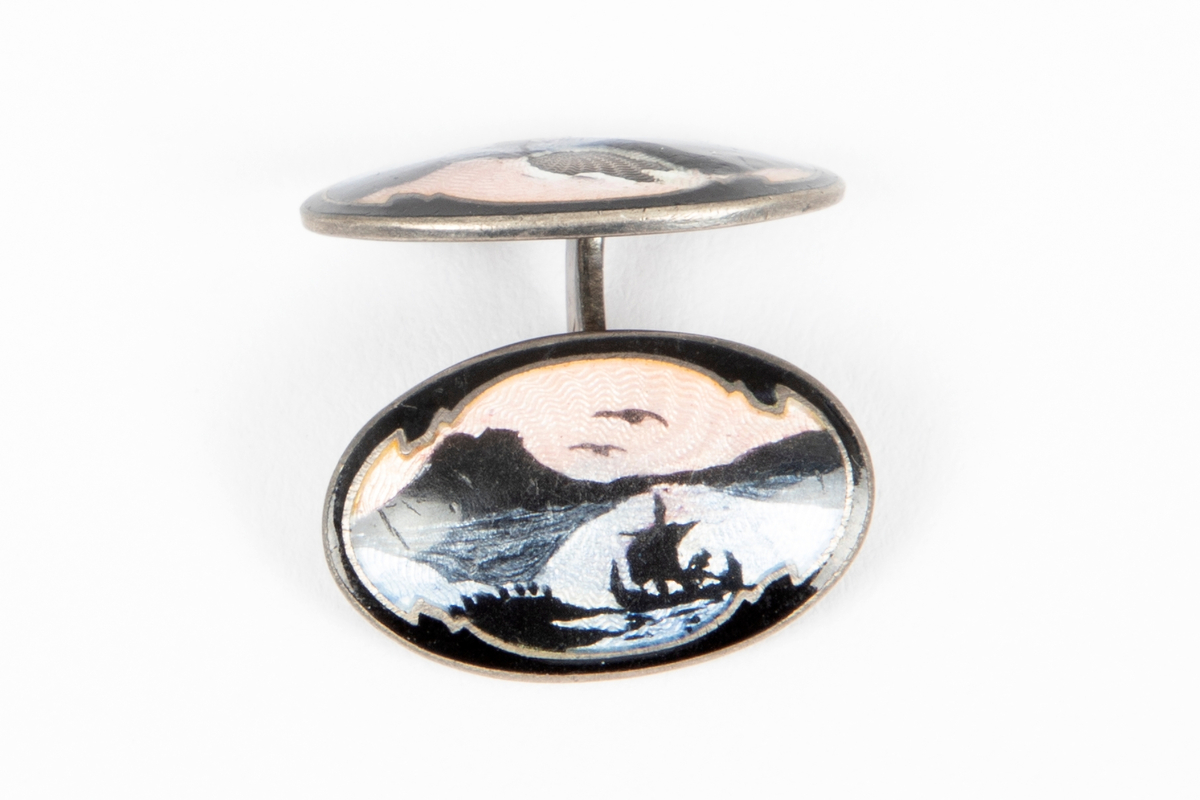 Ovalformet mansjettknapp i sølv med emalje over guillochering. Landskapsmotiv med vikingskip i svart mot rosa og lyseblå bunn.