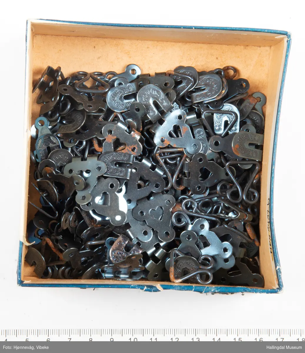 Svarte metallhekter som ligger i en pappeske med blått lokk.