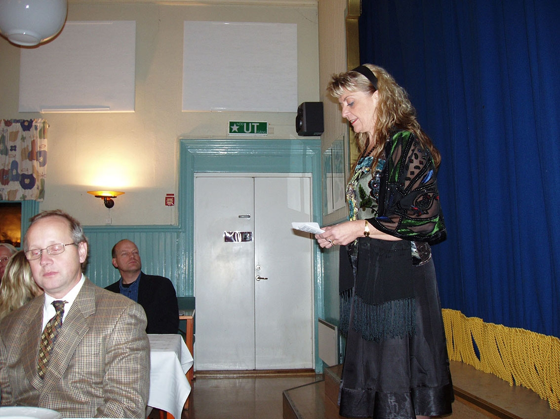 En kvinna håller ett tal till middagsgäster. Kvinnan är ordförande i Stiftelsen Grenna Museum.