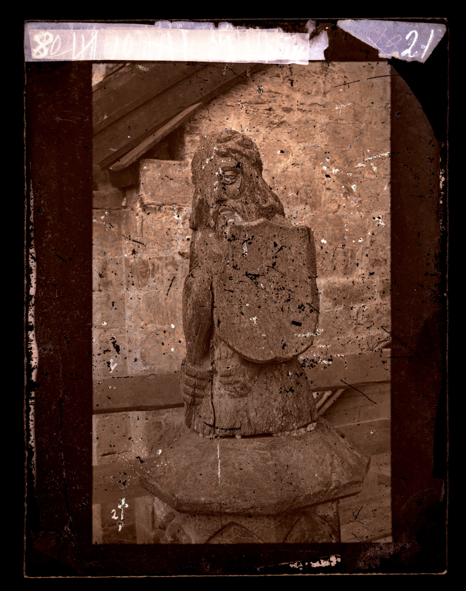 Statue fra hjørnefial på søndre oktogonkapell. Figuren forestiller en kriger i halvfigur. Han har klubbe, skjold og hjelm. Mannen har bart, skjegg og hår i fletter. Bilde tatt før restaurering (oktogonen ble restaurert i perioden 1872-1877).