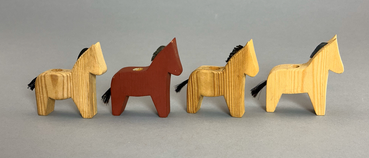 Fyra ljusstakar i form av hästar med tagelsvans och man av skinn. Häst a) är trären och dekorerad med röda och blå blommor på ena sidan - se bild 3-7, häst b) är rödmålad - se bild 8-11 och c-d) är trärena - se bild 12-16 och 17-21.