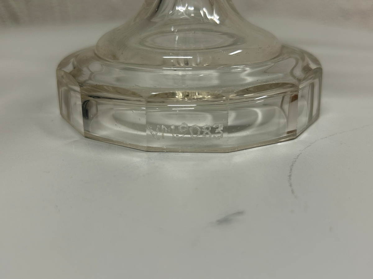 Tolvkantig skål av ofärgat glas på högt ben. Mynningskanten är fasettslipad och uddformad. Lambrequinform.