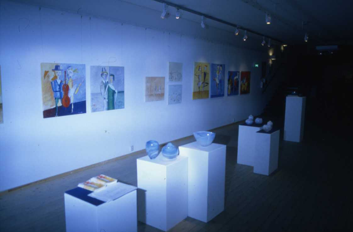 Oljemålningar och konstglas i en utställning.