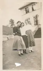 Tre kvinner står sammen og holder rundt hverandre foran et h