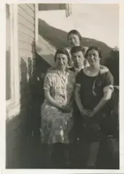 Tre kvinner og en mann sitter sammen ute ved siden av et hus