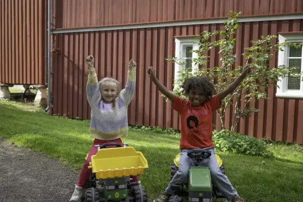 To barn på leketraktorer som smiler