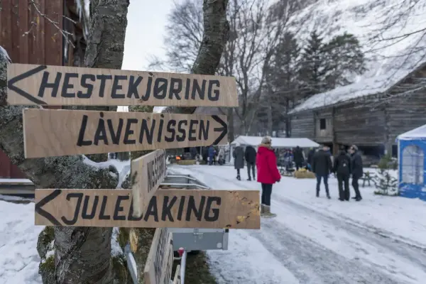 Piler som peker mot hestekjøring, låvenissen og julebaking. Snø og mennesker i bakgrunnen.