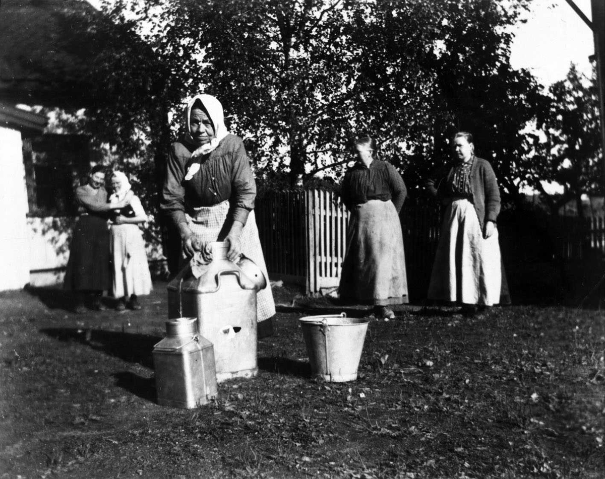 Rengjøring av melkespann på Valstad Budeie Helene Olsen. Fire kvinner står i bakgrunnen.