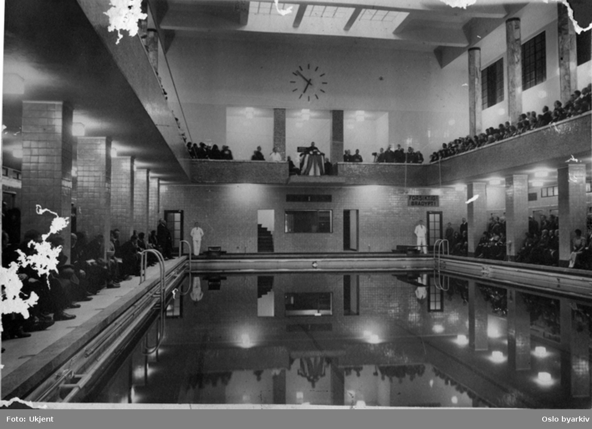 Storslått åpning av svømmehallen i det nyeTorggata bad med kommunestyre, badeutvalget, betjening og gjester. Badet var det første med 25 m basseng og hadde blant annet romerbad, dusj og egne avdelinger for karbad. Talestol på fem-meteren. De to tremeters stupebrettene var ennå ikke montert. Svømmehallen ble tatt i bruk 1. desember 1931 og hermed var hele anlegget i drift.