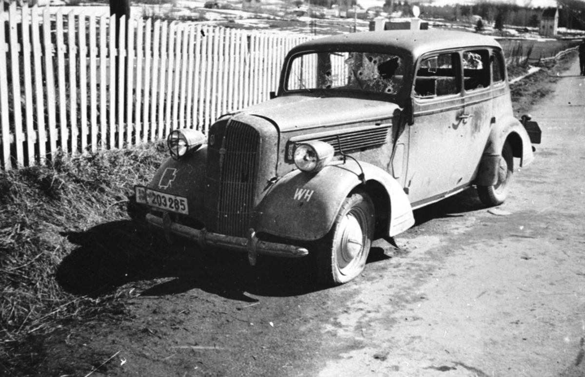 Første tyske bil som kom til Brumunddal under krigen. En Opel Super Six 1936-38. Full av kulehull. Foran stakittet på Buttekvern gård, april 1940.