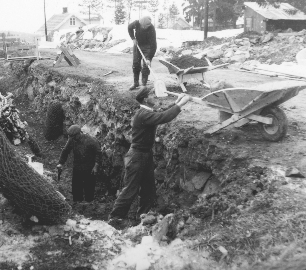 Pinnerudvegen i Moelv. Graving og legging av ny vann og kloakkledning ca. 1952-1955. Graving for hånd, trillebår, spader. Grøft. 