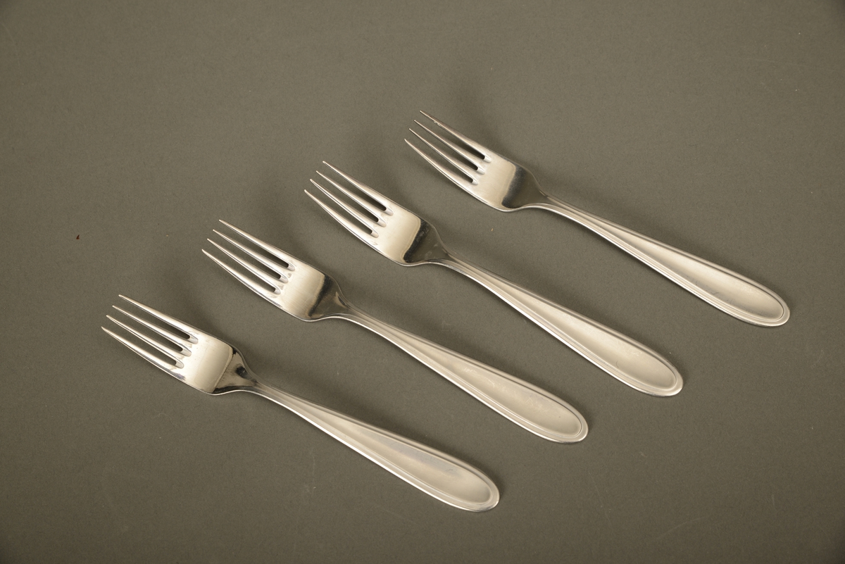 Fire gafler i rustfritt stål fra den norske produsenten Norstaal. Gaflene er del av innholdet i en campingkoffert. De er festet til lokket av kofferten med reimer.