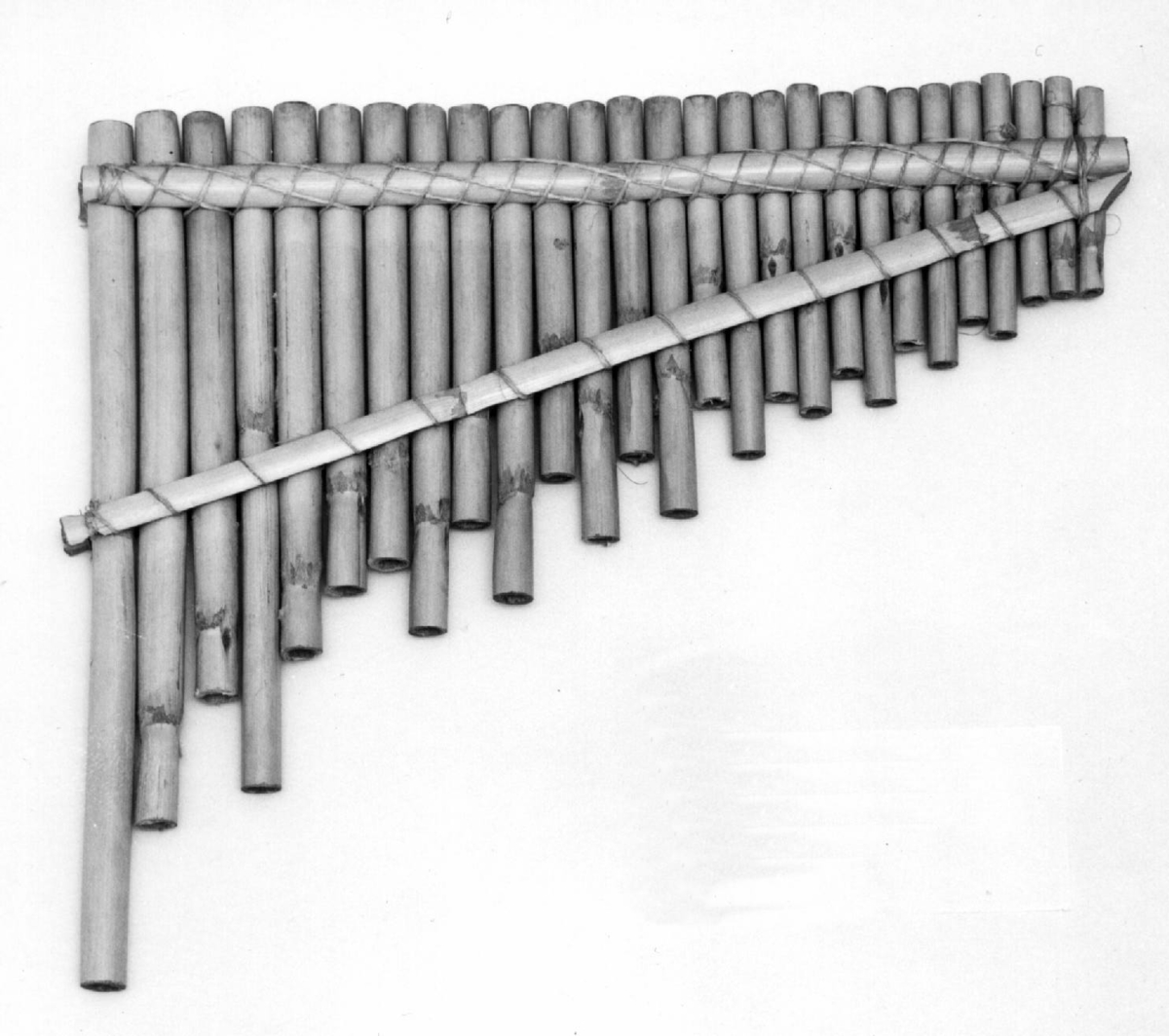 Består av 27 parallelle bambusrør av avtagende lengde, bundetfast til hverandre i flåteform. Lukket i nedre ende.

