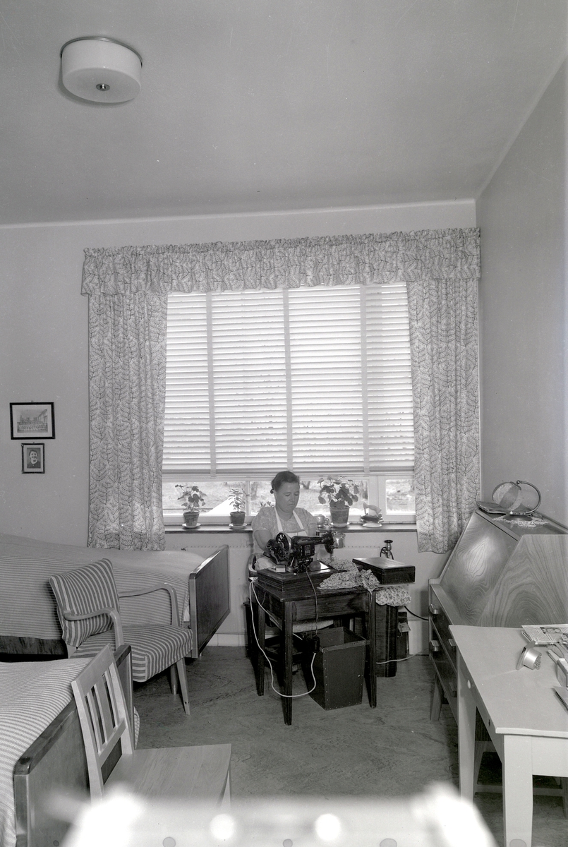Østlandske Vanførehjem, Ottestad i Stange. Interiør, pasientrom, ukjent kvinne symaskin, 25. 04. 1950. 
Foto for Aftenposten. 