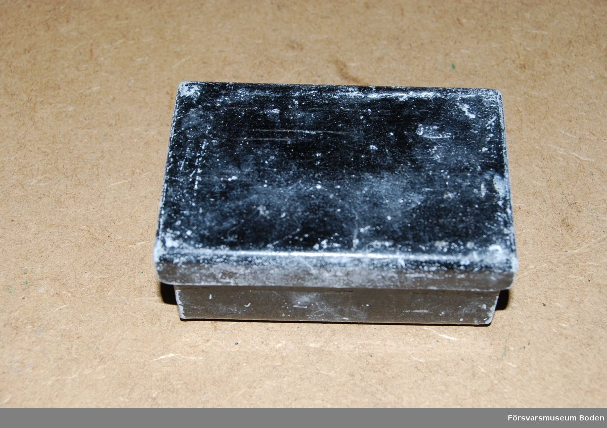 Svartlackerad ask av bly indelad i två fack, innehållande ett antal oanvända Kodak röntgenplåtar för tänder.