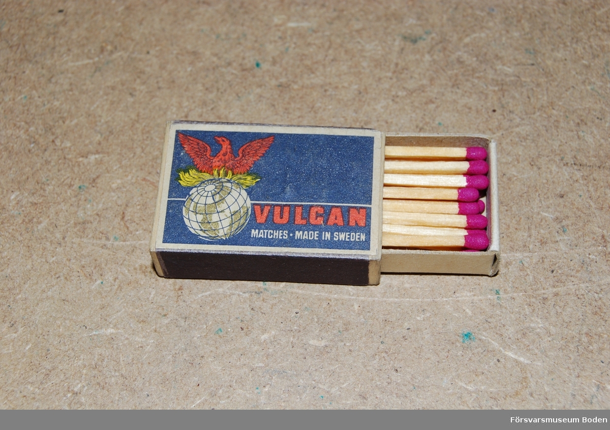 Liten ask 42 x 28 x 12 mm med blå och röd etikett för varumärket Vulcan. Tändstickorna har rött svavel.