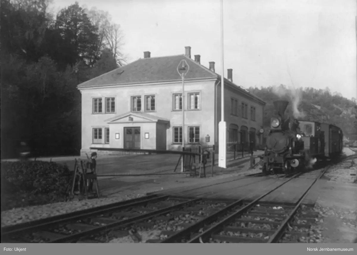 Arendal stasjon med planovergangen, den nye stasjonsbygningen og et damplokomotiv av type X