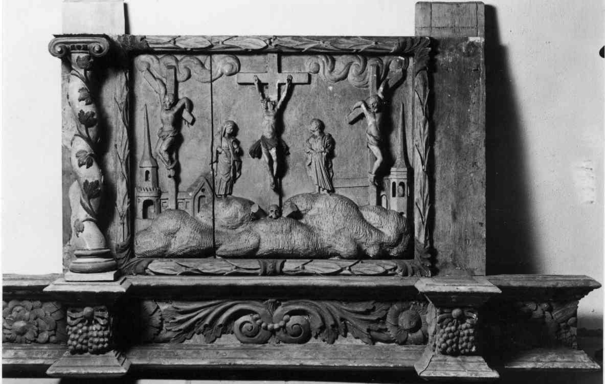 Nattverden. Jesus og disiplene sitter ved et dekket langbord. Jesus er sentralt plassert med glorie rundt hodet. Figur av evangelisten Lukas med oksen som sitt symbol til venstre. 
