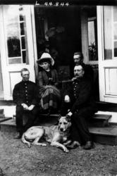 Gruppeportrett, person gruppe med hund i inngangsparti. Fra 