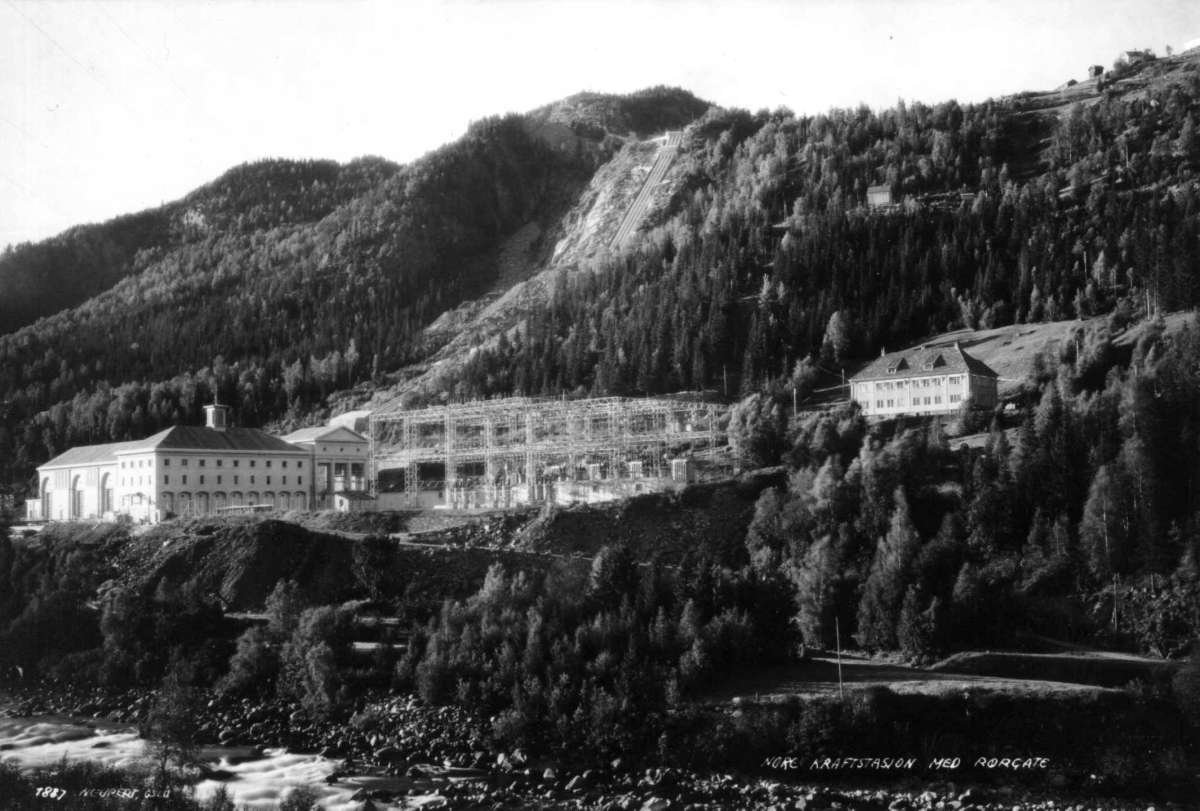 Nore kraftstasjon, Nore, Nore og Uvdal. 1930. Oversiktsbilde. Kraftgate. Skog og fjell i bakgrunnen. Beggyelse. Vei og elv i forgrunnen.