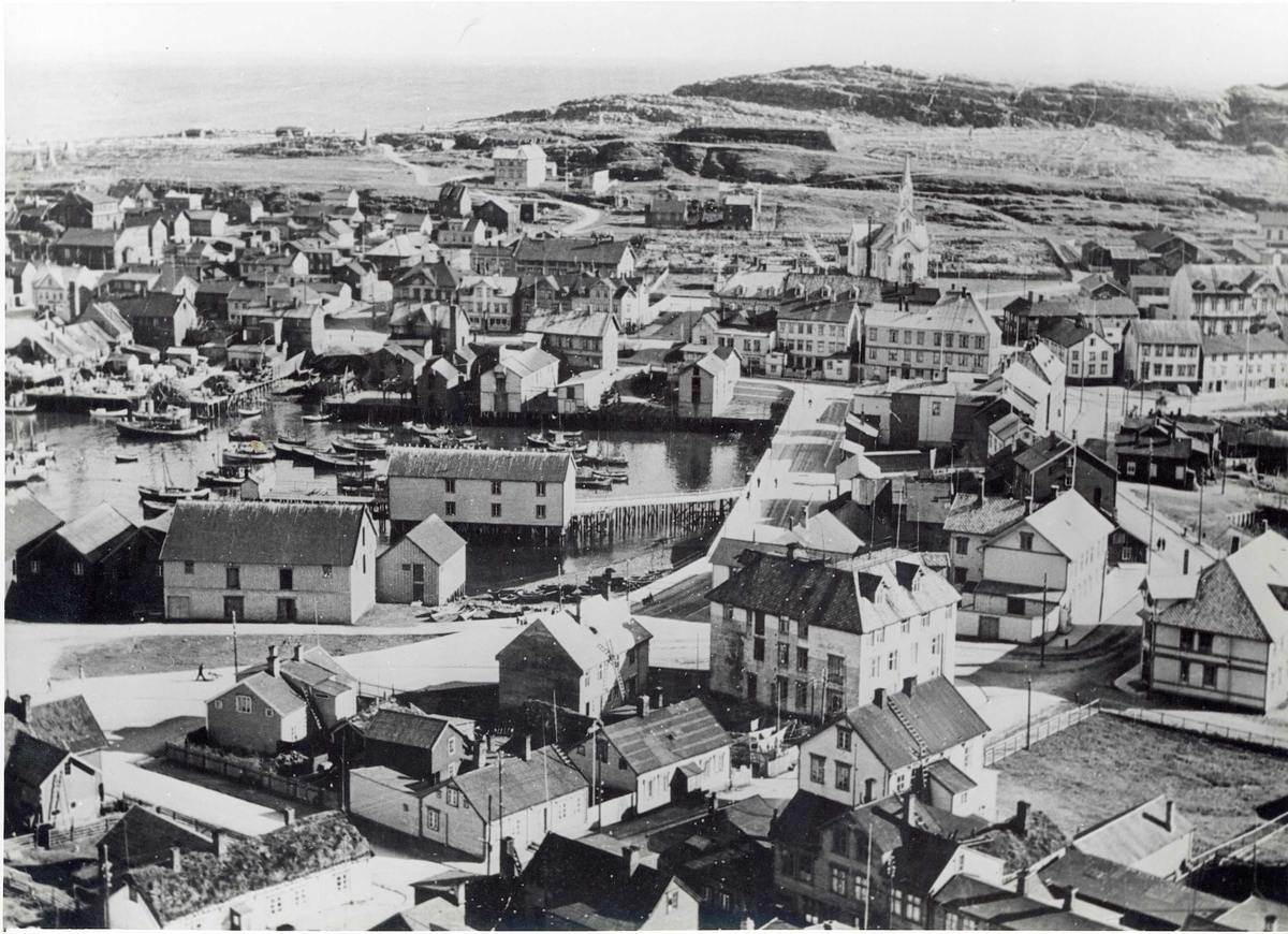 Vardø, Finnmark før bombingen 23.08.1944 og brenningen oktober 1944. Bybebyggelse bestående av trehus, kirke og havn med fiskebåter.
