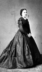 Visittkort. Portrett av kvinne i lang svart kjole. Stående i