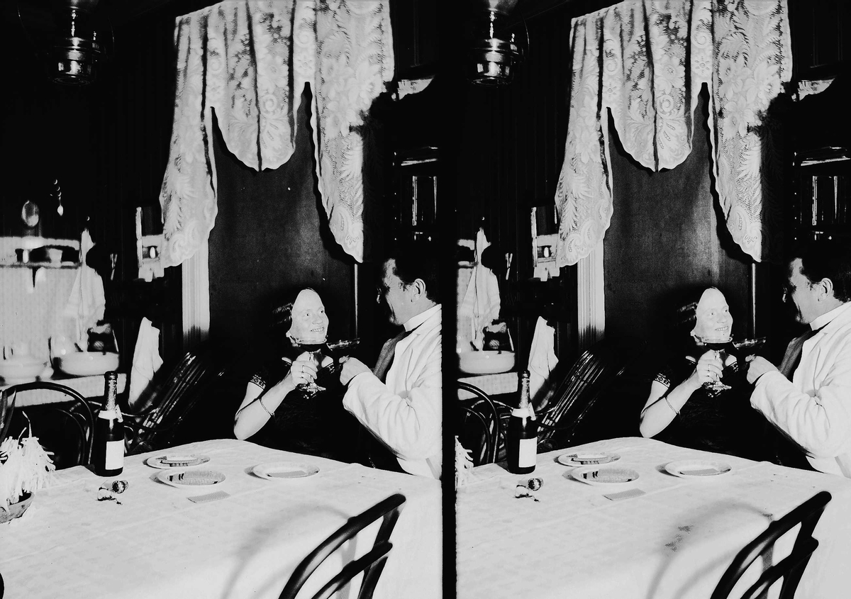 Interiør, mann og kvinne sitter ved bord og skåler, Axel Q. Wiborg med antatt sin kone Margrethe. Vaskestell i bakgrunnen. Ukjent sted.