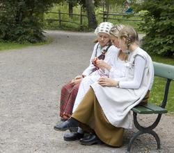 Levendegjøring på museum.Tre jenter på en benk, den ene vis