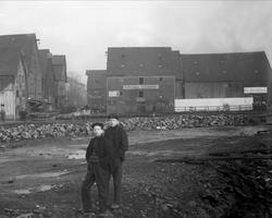 To gutter i strandkanten ved lavvann. Lagerbygninger i bakgr