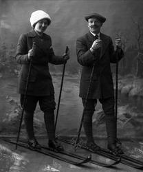 Gruppeportrett, mann og kvinne i skiutstyr i studio. Begge i